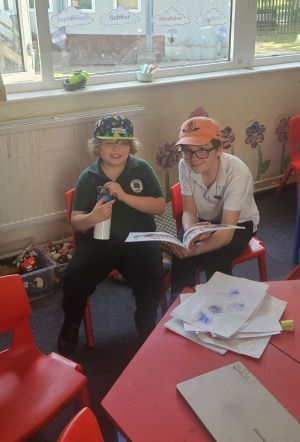 Student supporting younger student with reading